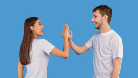Portrait of beautiful young couple giving high five at studio
