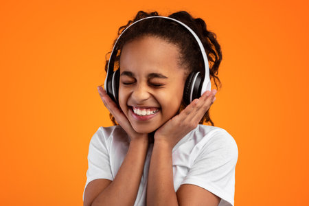 Smiling Young Black Girl Listening To Music In Headphonesの写真素材