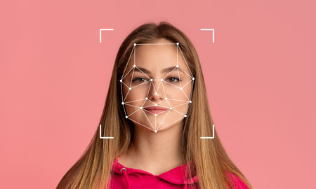 Young woman analyzed with facial recognition against a pink backgroundの写真素材