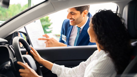 Young woman sitting inside car, having conversation with sales manager