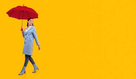 Portrait of excited young woman walking with yellow parasolの写真素材
