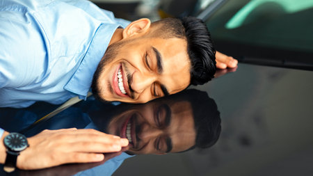 Delighted young arab man hugging car of his dream