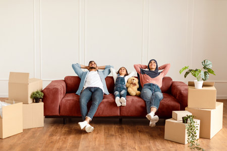Family relaxing on couch in new home with cardboard boxesの写真素材