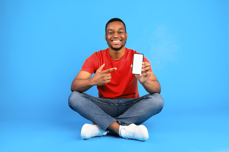 African Man Showing Phone With Empty Screen Over Blue Backgroundの写真素材
