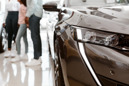 Young black family with child buying new car, consulting salesman at auto dealership, selective...