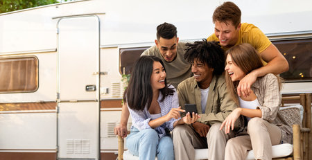 Young multinational friends using smartphone near RV outdoors, having online video call, enjoying...