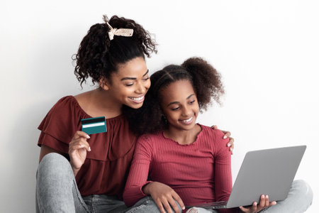 Happy black mother and daughter shopping online together, closeupの写真素材