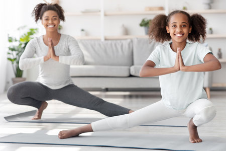 Sporty black family mother and daughter exercising at homeの写真素材