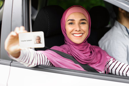 Joyful Islamic Lady In Hijab Demonstrating Driver Licence At Cameraの写真素材
