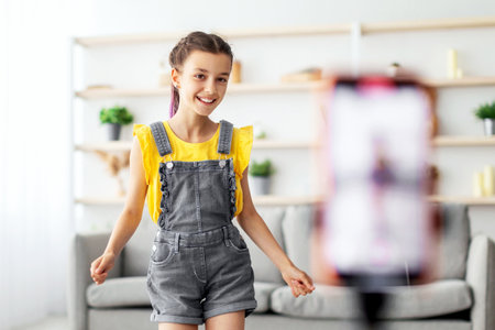 Positive girl dancing at camera filming vlog on cellphoneの写真素材