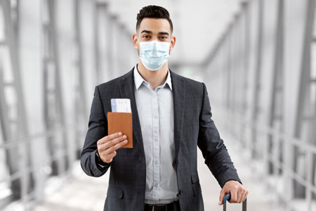 Pandemic Travels. Young Arab Man Wearing Protective Medical Mask Standing In Airport