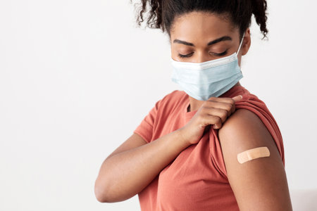 Black lady patient looking at medical plaster on her armの写真素材
