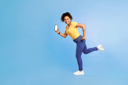 Huge online sale. Full length of happy young African American woman with blank smartphoneの写真素材