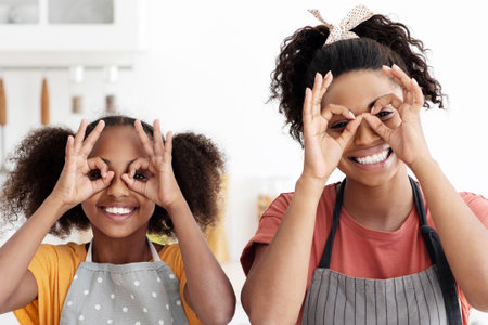 Black mother showing her teen daughter how to make cookiesの写真素材