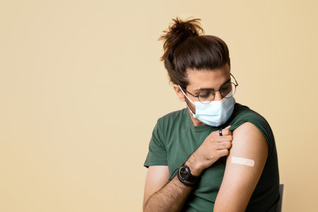 Middle-eastern guy in face mask looking at band on shoulder