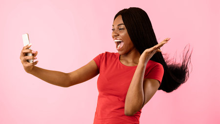 Joyful African Woman Using Smartphone Making Selfie On Yellow Backgroundの写真素材