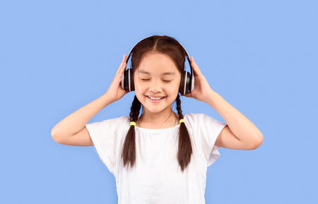 Little Girl In Earphones Enjoying Music On Purple Backgroundの写真素材