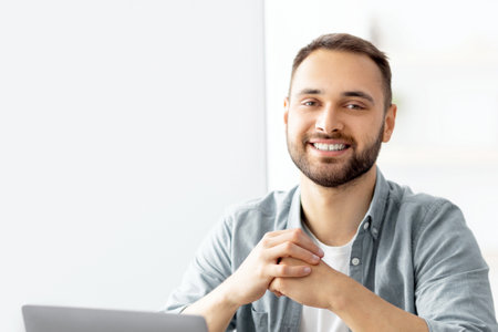 Positive male teacher giving English lesson online, using laptop at home office. Modern remote...