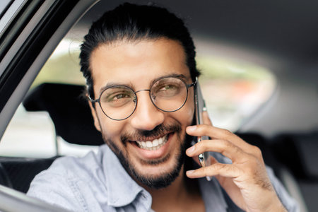 Closeup of cheerful man sitting in taxi, talking on phone