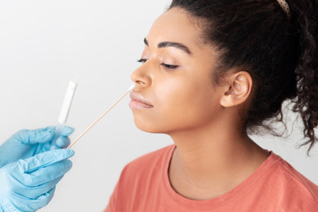 Doctor taking nasal swab for coronavirus sample from female patientの写真素材