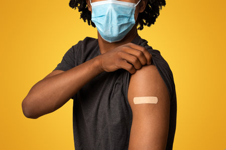 After Vaccination. Black Guy In Medical Mask Showing Arm With Adhesive Bandage