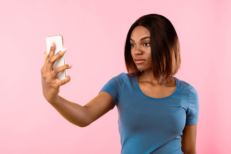 African Lady Unlocking Phone Via Face ID App, Yellow Backgroundの写真素材