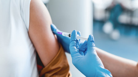 Young Woman Receiving Vaccine Injection Sitting With Doctor Indoorの写真素材