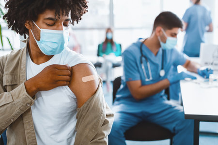 African American Guy Showing Vaccinated Arm With Adhesive Bandage In Hospitalの写真素材
