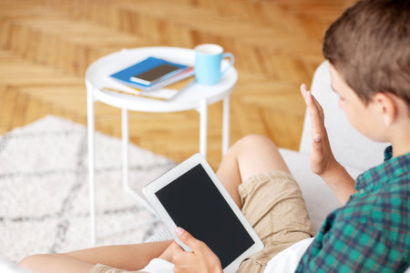 Boy waving to digital tablet with empty screen