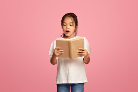 Focused diverse schoolkids reading books over pink backgroundの写真素材