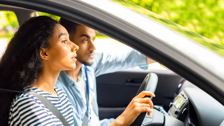 Nervous young lady driving school student driving car with instructor