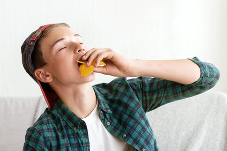 Teen guy enjoying chips while watching football gameの写真素材