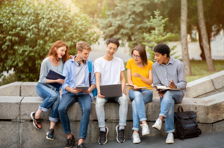 Chinese Student Showing Educational Website On Laptop To Coursemates Outsideの写真素材