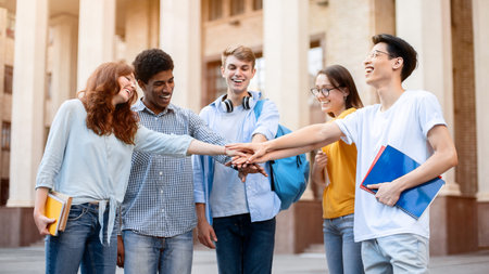 Students Holding Hands Standing In Circle Outside University Buildingの写真素材