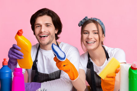 Joyful couple sitting at table with lot of detergents, ready for cleaning