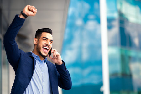 Ecstatic businessman having phone conversation with business partner, copy spaceの写真素材