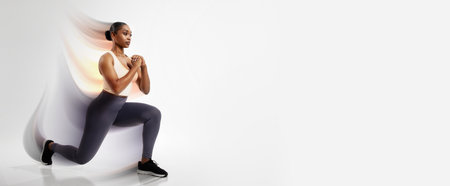 African American fitness woman stretching legs performing forward lunges, studioの写真素材