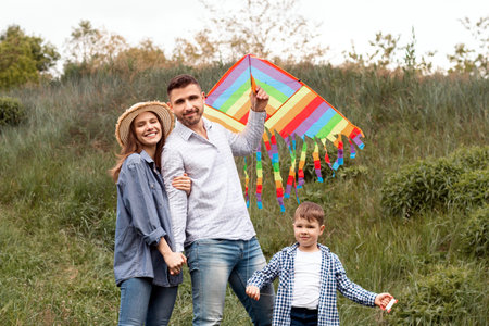 Portrait of happy family with bright kite in countrysideの写真素材