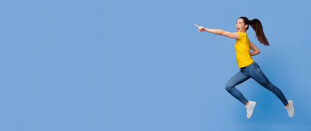 Excited Asian Girl Jumping And Pointing Aside At Copy Space