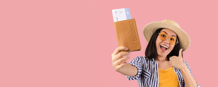 Asian woman holding passport with boarding pass showing thumbs upの写真素材
