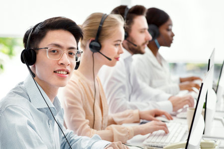 Asian call centre manager smiling and looking at camera in light office, space for textの写真素材