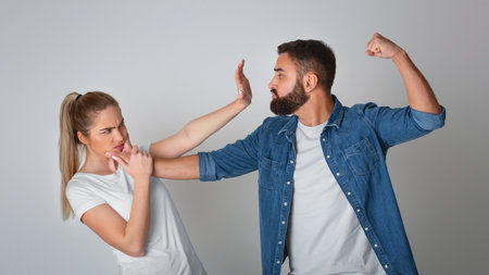 Stop domestic violence. Decisive woman defends herself from attacker man, waves his fistの写真素材