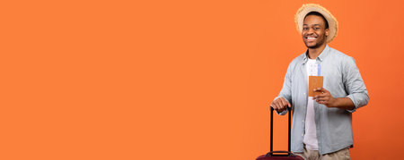 Young man in casual clothes with suitcase, passport and tickets over orange studio backgroundの写真素材