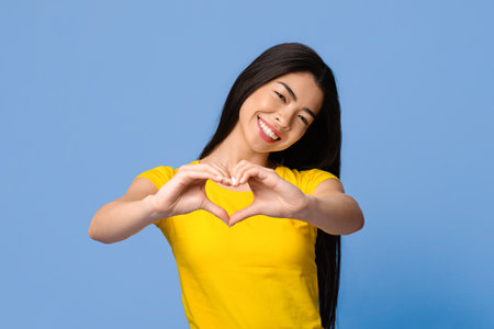 Cheerful young korean woman shaping hands like heart, showing love gestureの写真素材