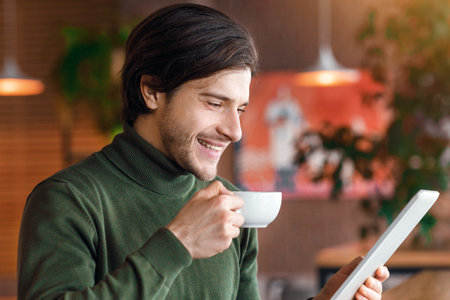 Happy businessman reading news while drinking morning coffeeの写真素材