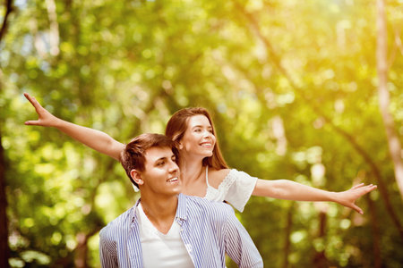 Caring boyfriend carrying girlfriend on his back in nature, copy spaceの写真素材
