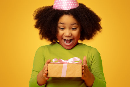 Birthday Surprise. Overjoyed Little Black Girl In Party Hat Holding Gift