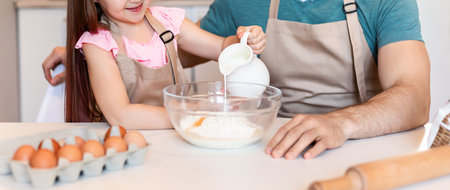 Dad And Daughter Baking Cake Adding Milk To Dough Indoorの写真素材