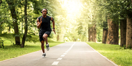 Concentrated sportsman running by park path in summerの写真素材