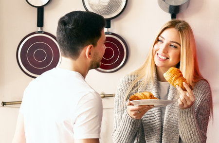 Couple enjoying a cozy breakfast with croissants in a bright kitchenの写真素材